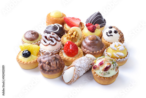Mignon pastry, assortment of small desserts with berries, chocolate,  cream and whipped cream isolated on white background, close-up.
