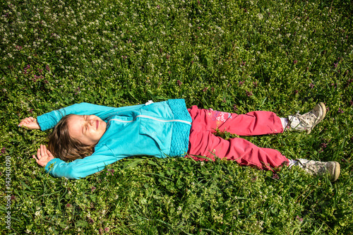 Obraz na plátně Happy Little girl resting on the grass