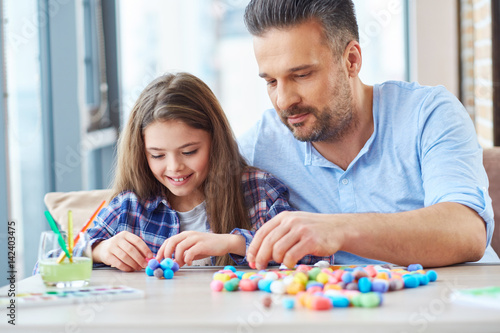 Beautiful little girl with her father playing with colored set for creativity