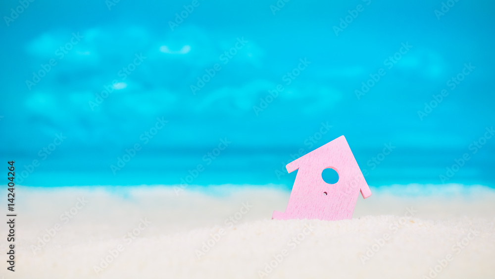 Naklejka premium Symbol of little lilac house on the sand with bright cloudy blue painted sky background
