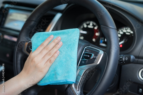 Hand with microfiber cloth cleaning car.woman cleaning car interior - car detailing and valeting concept in car wash car care station ,selective focus,vintage color