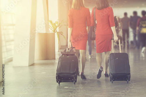 air hostes, women pulling suitcase in modern airport terminal. Travelling  wearing red style clothes walking away with his luggage while waiting for transport.selective focus,vintage color photo