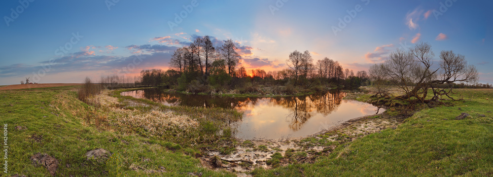 Fototapeta premium Spring sunset panorama. Small river in evening