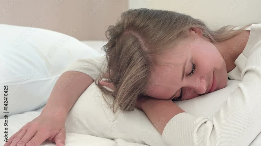Relaxed young blonde girl sleeping on white bed at home or in hotel room Relaxed young blonde girl sleeping on white bed at home or in hotel room