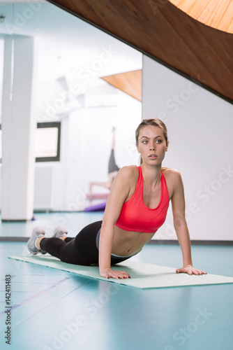 Young woman doing pilates exercises on the floor at the gym