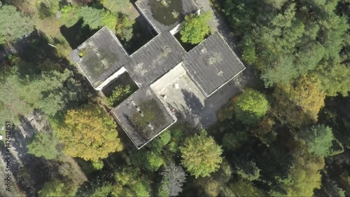 Flying over the the building in the middle of the forest. Aerial survey of the exterior of abandoned hospital.A lonely building view.The building was abandoned nearly twenty years ago, but never photo