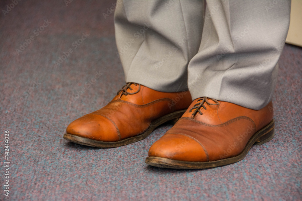 Bright brown men's shoes with gray pants. Groom outlook