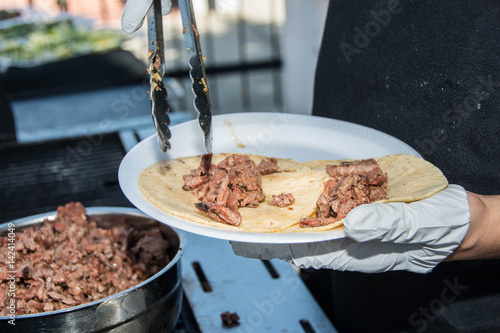 Cook puts the meat into the tacos