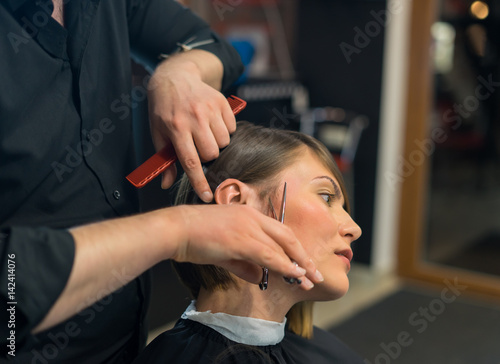 Male hairdresser is preparing for haircut of Beautiful woman in the beauty salon.