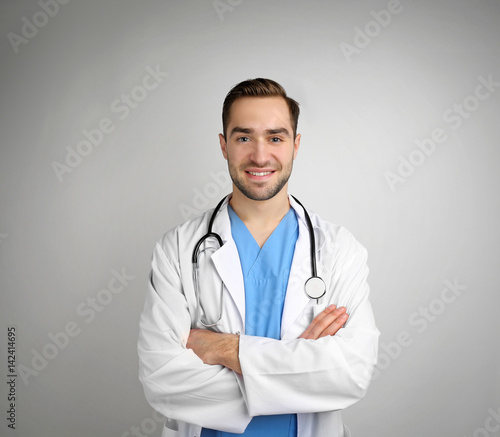 Handsome young doctor on light background © Africa Studio