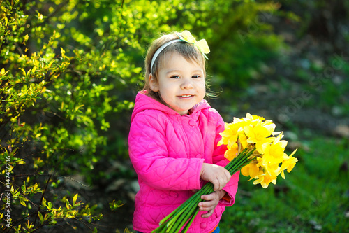 Cute young girl With a bouquet of yellow daffodils in spring garden