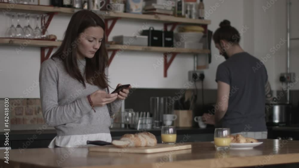 Young couple looking at smartphone together over breakfast Young couple looking at smartphone together over breakfast