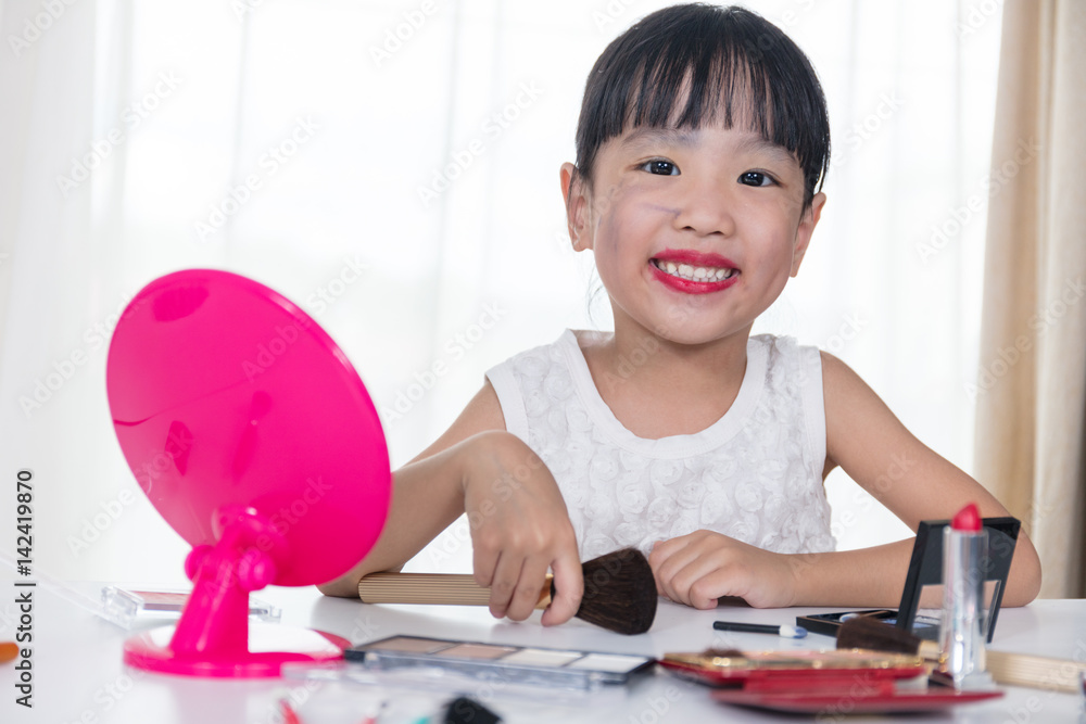 Asian Chinese little girl applying makeup with cosmetics Asian Chinese little girl applying makeup with cosmetics