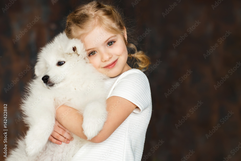 Little girl hug a samoyed puppy Little girl hug a samoyed puppy