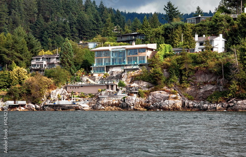 A village on a rocky beach in the  Strait of Georgia in West Vancouver  British Columbia, a coastline and a forest.  photo