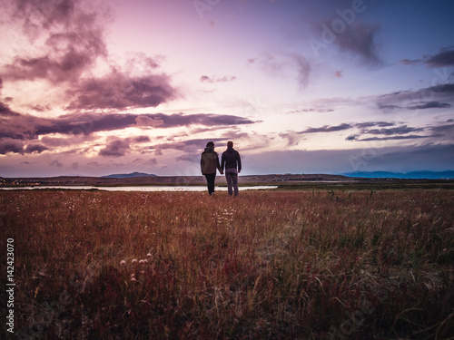 Couple watching sunset in the field