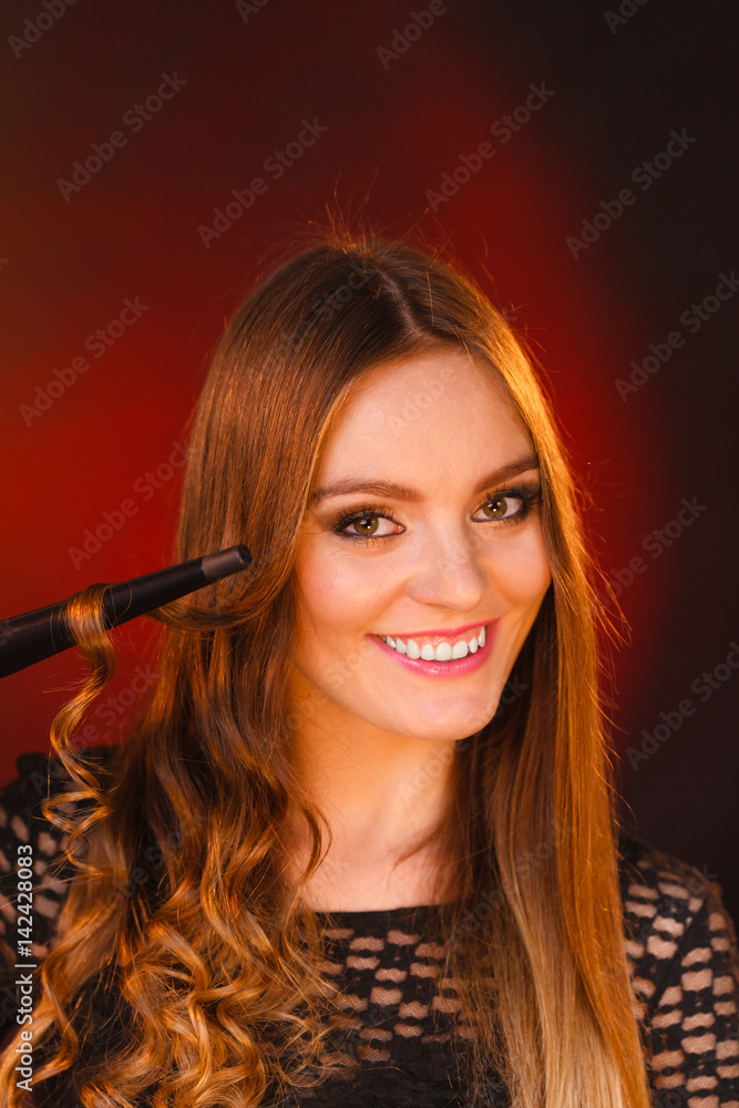 Obraz premium Happy woman curling her long brown hair