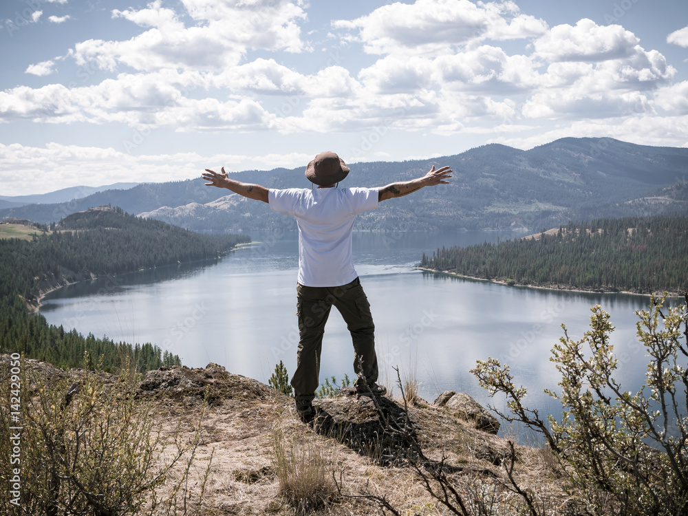 Man Holding Hands Out Overlooking Epic Nature View of Massive Mountain Lake