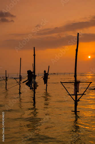 Silhouettes of the traditional Sri Lankan stilt fishermen at the sunset in Weligama, Sri Lanka. Stilt fishing is a method of fishing unique to the island country of Sri Lanka