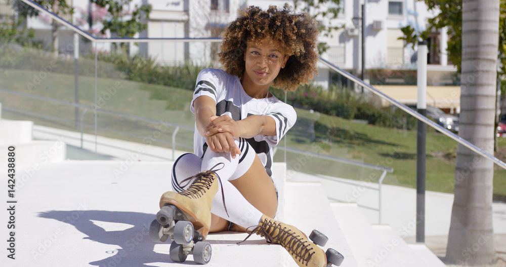 Smiling female sitting on white stairs wearing roller skates, knee-high  socks and t-shirt looking at camera. Stock Photo | Adobe Stock