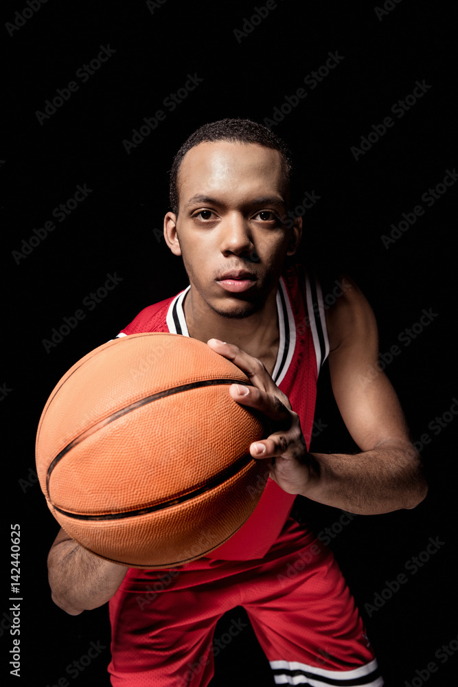 Young athletic man in uniform playing basketball on black Young athletic man in uniform playing basketball on black