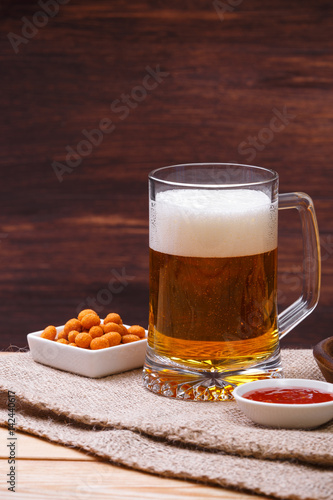 Glass of beer. Mexican salsa nuts. Appetizer with sweet salsa or chilli sauce. Mug or pint of ale. On rustic wooden background.