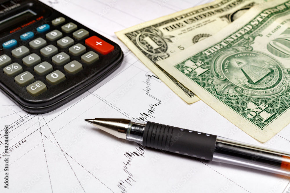Fragment of electronic calculator with ball pen and US dollars banknotes on the background of currency growth schedule Fragment of electronic calculator with ball pen and US dollars banknotes on the background of currency growth schedule
