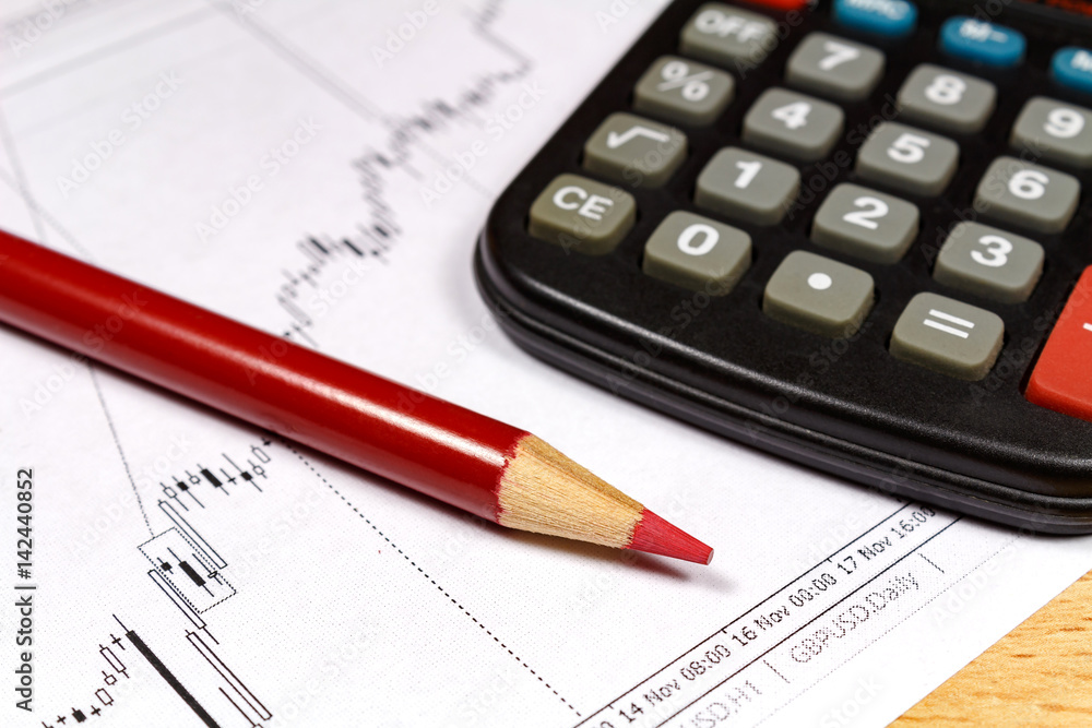 Fragment of electronic calculator with red pencil on the background of currency growth schedule. Focus in the pencil Fragment of electronic calculator with red pencil on the background of currency growth schedule. Focus in the pencil