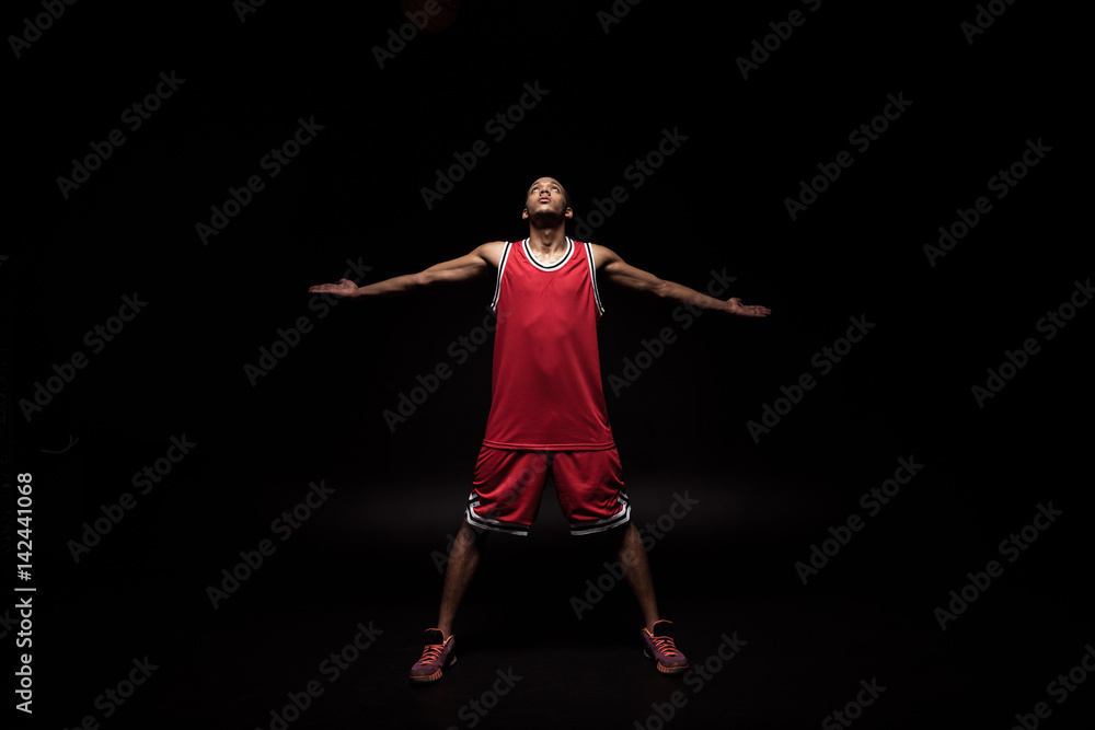 african sporty basketball player in sports uniform on black