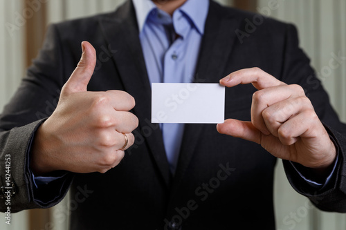 Businessman holding visit card. Man showing blank business card. Person in black suit showing thumb up. Mock up design.