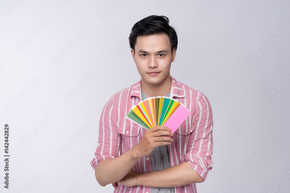 Asian graphic designer holding color palette over gray background. Asian graphic designer holding color palette over gray background.