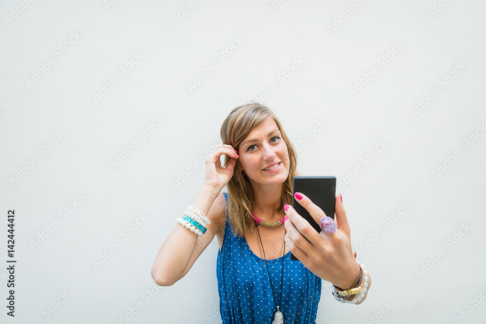 Cute girl using cellphone in front of a white wall - facade. Cute girl using cellphone in front of a white wall - facade.