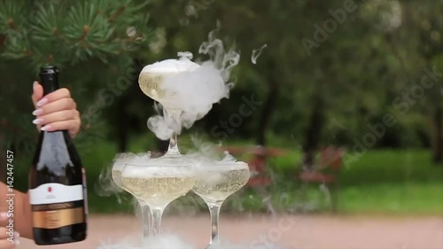 Glasses Of Champagne Smoking. Champagne glasses. Smoke Billowing Over A Champagne Flute. Catering service. Wedding slide champagne for bride and groom outdoors. Colorful glasses for alcohol. Business photo