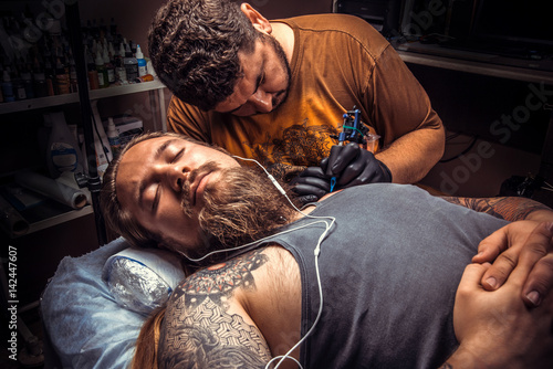 Tattooer works in tattoo parlor