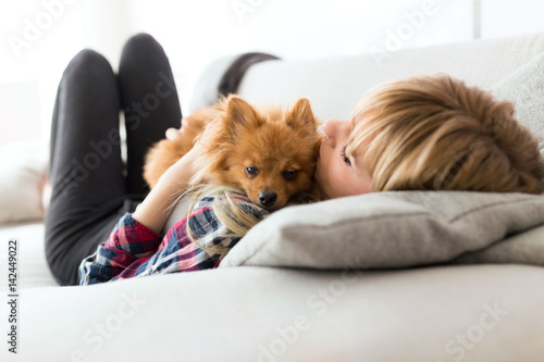 Beautiful young woman with dog playing at home.