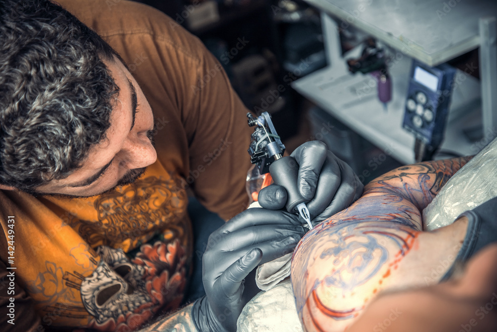 Professional tattoo artist works in tattoo parlor