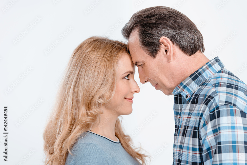 side view of stylish mature couple looking at each other on white