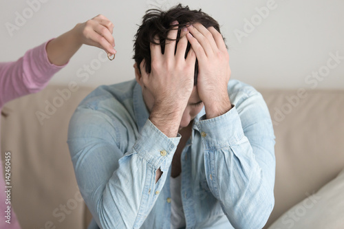 Obraz na plátně Woman gives back wedding ring to sad husband and leaving, engagement cancelling, man depressed and upset, covers face with hands