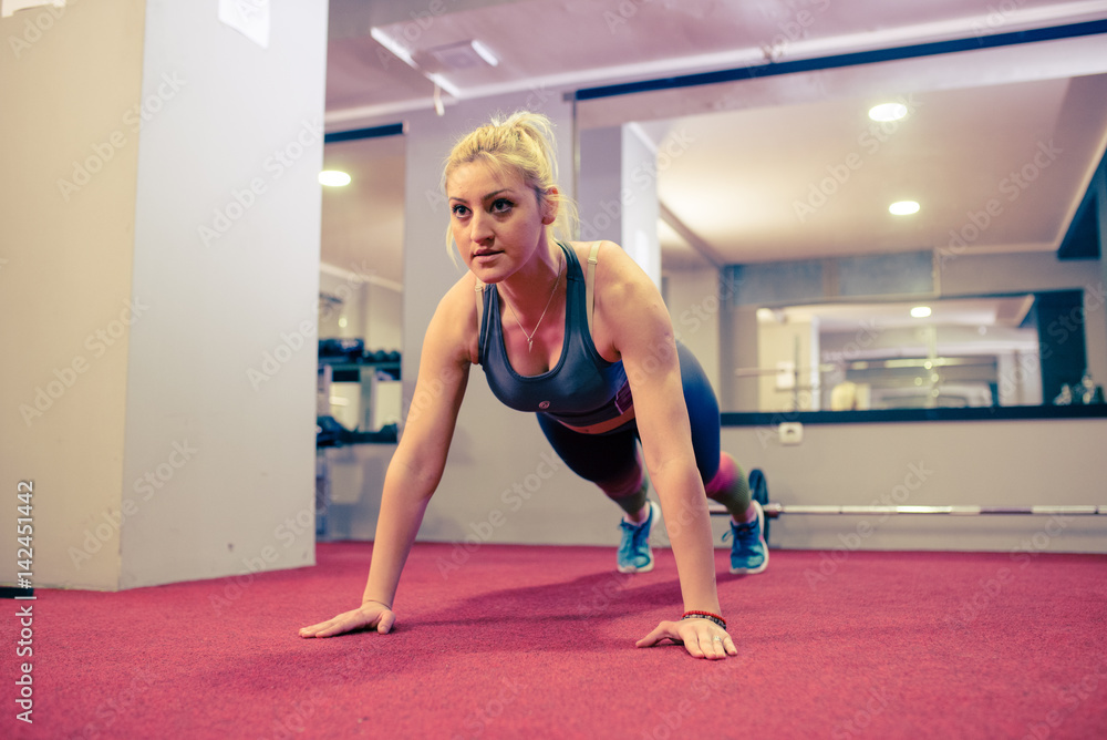 Obraz premium Blonde girl doing push ups at gym