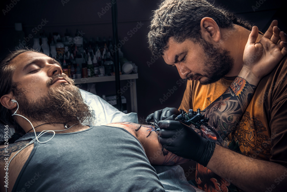Professional tattoo artist showing process of making a tattoo in tattoo