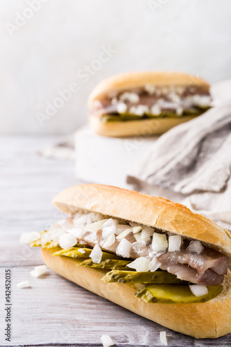 Traditional dutch snack, seafood sandwich with herring, onions and pickled cucumber. Broodje haring. Copy space.
