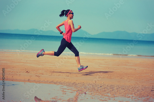 Healthy lifestyle young fitness woman running at morning beach