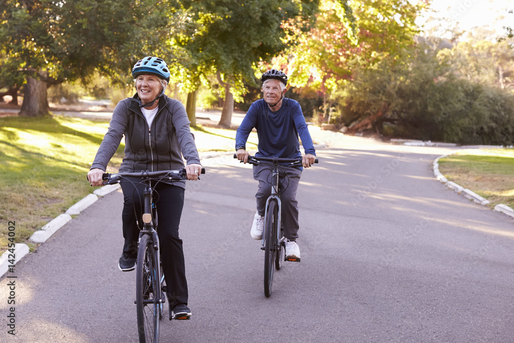 Fototapeta premium Front View Of Senior Couple Cycling Through Park Together