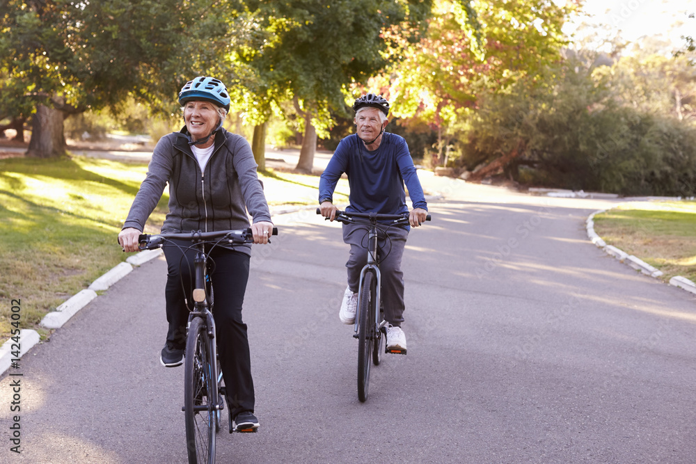 Front View Of Senior Couple Cycling Through Park Together