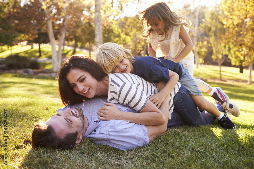 Mother And Children Lying On Father In Park Mother And Children Lying On Father In Park