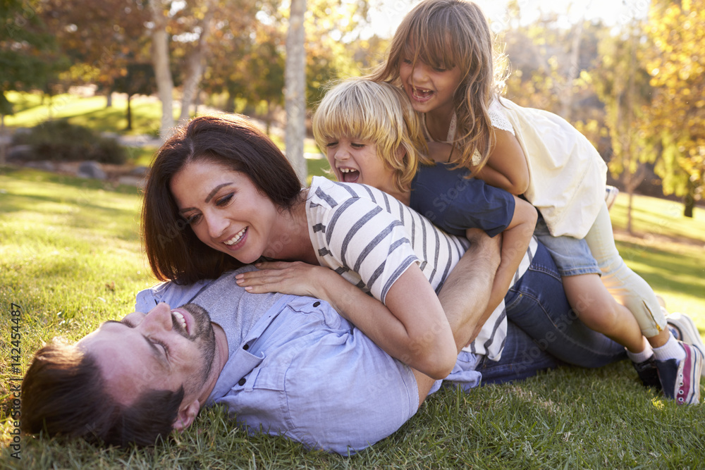 Fototapeta premium Mother And Children Lying On Father In Park