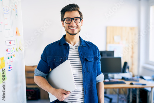 Canvastavla Happy young man, web designer standing with laptop