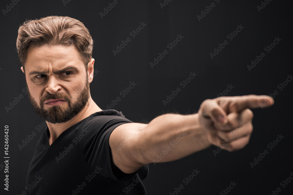 angry bearded man pointing on black with copy space