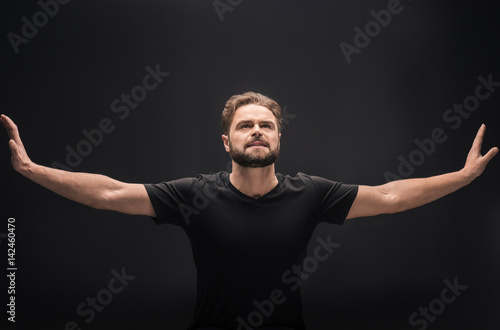 Front view of upset bearded man with outstretched hands on black