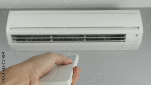 4k of hand holding remote control and turning on air conditioner at home